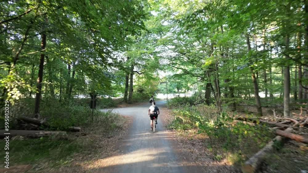 Single bicyclist driving on a path in the middle of a green forest Single bicyclist driving on a path in the middle of a green forest