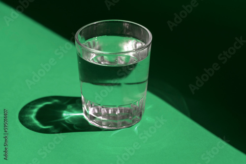 Glass of water on green background