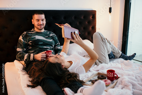Young couple relaxing on a bed with warm drinks