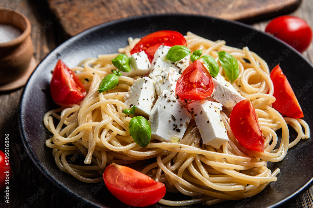 Spaghetti with feta cheese and tomatoes in a plate. Italian pasta Spaghetti with feta cheese and tomatoes in a plate. Italian pasta