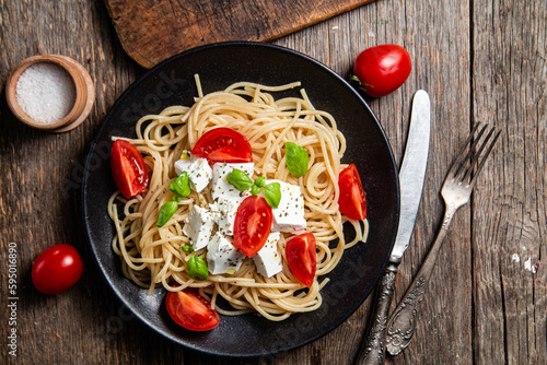 Spaghetti with feta cheese and tomatoes in a plate. Italian pasta photo