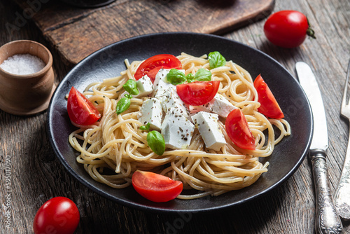 Spaghetti with feta cheese and tomatoes in a plate. Italian pasta