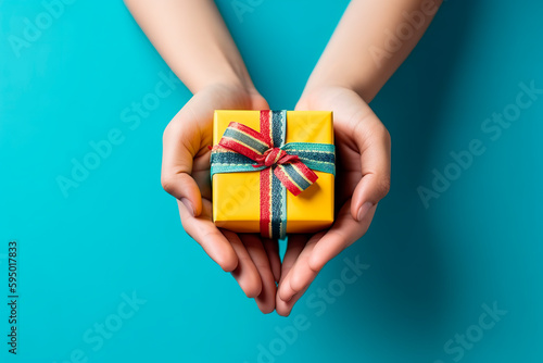 Woman hands holding gift decorated with ribbon on blue background, copy space. Flat lay, hands and present box, top view. Valentine or love, spring holidays, Christmas and birthday concept.