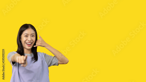 Call sign, Bright young asian woman inviting to call isolated on yellow background, Suggest to call or invite to apply for membership, Isolated on yellow background... © Puwasit Inyavileart