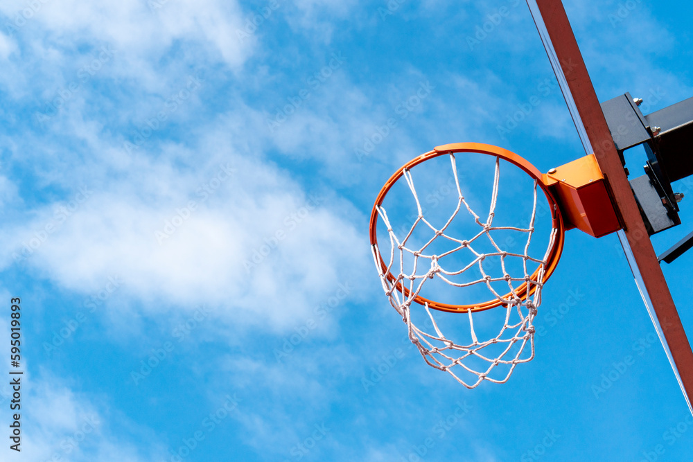 Basketball hoop against a blue sky from a low angle Basketball hoop against a blue sky from a low angle