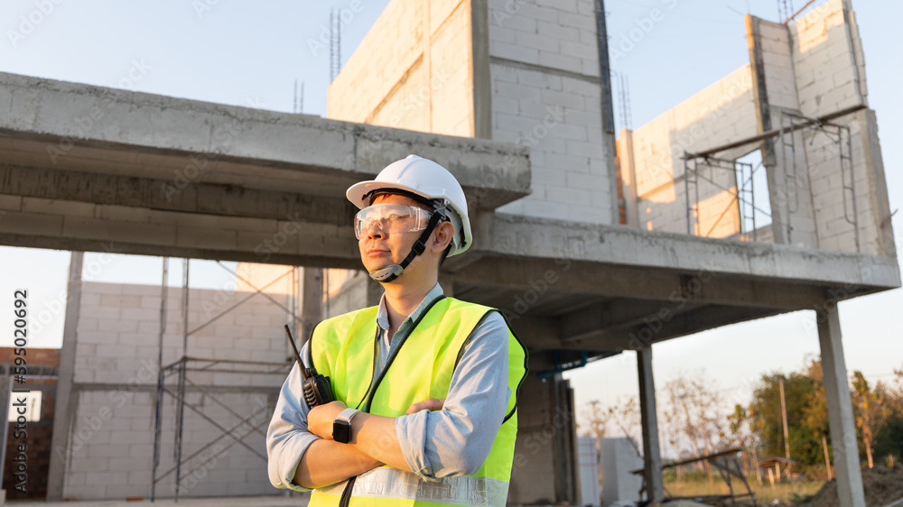 Skilled engineer inspects factory construction and uses a radio to chat with colleagues working on the field, Engineer working outdoors with blueprints and wearing protective safety gear. Skilled engineer inspects factory construction and uses a radio to chat with colleagues working on the field, Engineer working outdoors with blueprints and wearing protective safety gear.