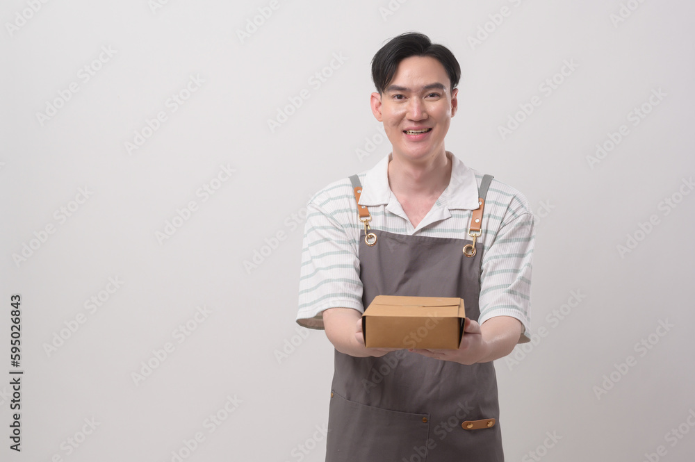 Portrait of young asian man wearing apron holding paper bag over white background studio, Save earth concept. Portrait of young asian man wearing apron holding paper bag over white background studio, Save earth concept.