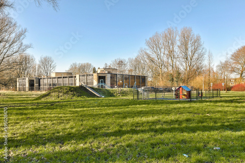 a house in the middle of an open field with trees and grass on both sides there is a playground area for children to play
