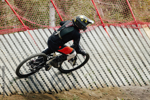 male rider rips turn on wood insloped corner in downhill race, summer extreme sports photo