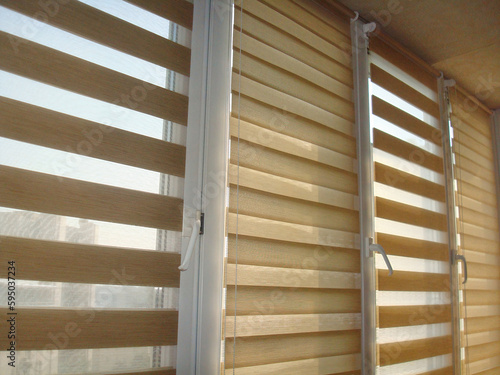 Double roller blinds closeup on the window in the interior. Dual roller shades beige color close-up. Zebra blinds. Duo system day and night.