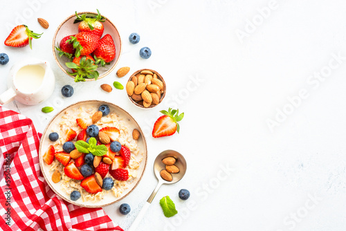 Oatmeal porrige with fresh berries and nuts on white.