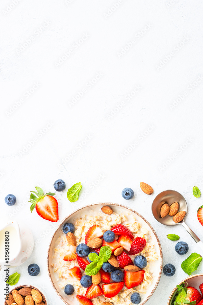 Oatmeal with fresh berries and nuts on white background. Top view with copy space. Oatmeal with fresh berries and nuts on white background. Top view with copy space.