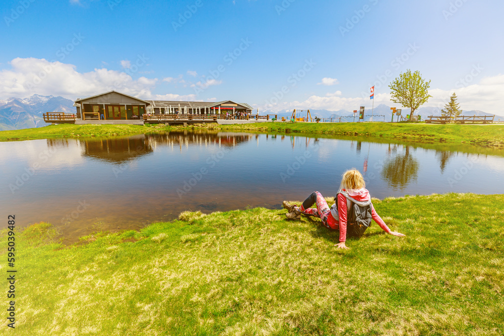 Fototapeta premium trekking woman in sporty dress, resting and enjoying Tamaro mount in Switzerland. Swiss pond in Foppa alp in Ticino canton. Top of Rivera station of cable car.