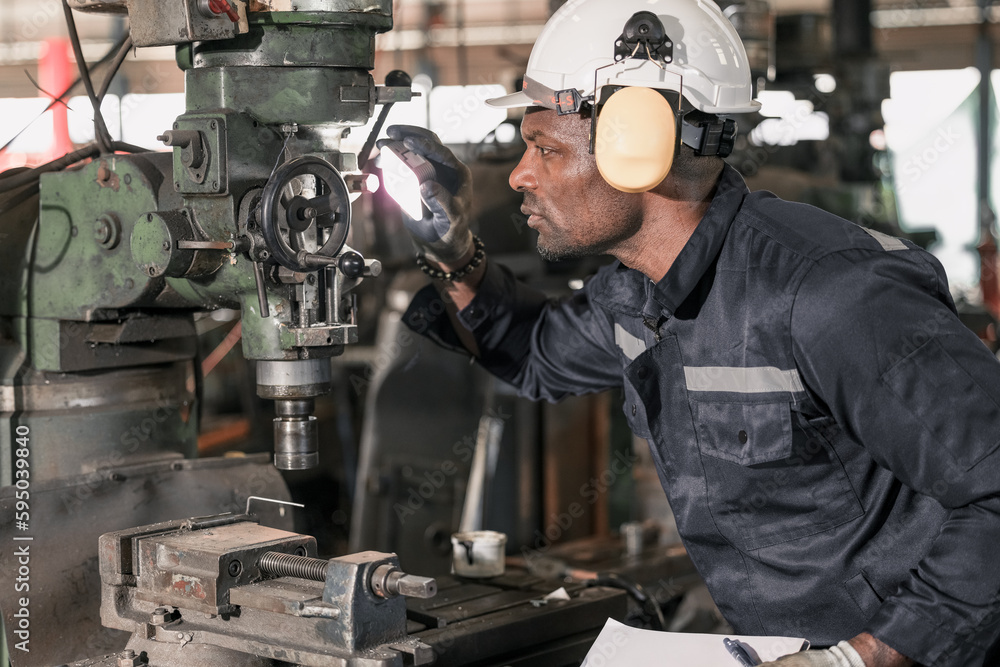 Skilled robotic technician spots the light on robotic components to do protective and corrective maintenance. Inspecting complex mechanical systems. Repairing and troubleshooting to resolve issues.