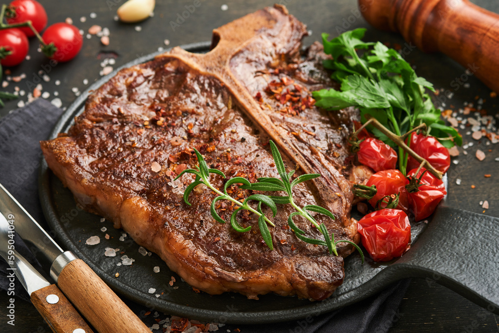Steaks T-bone. Sliced beef grilled T-bone or porterhouse meat steak with spices rosemary and pepper on black marble board on old wooden background. Top view. Mock up. Steaks T-bone. Sliced beef grilled T-bone or porterhouse meat steak with spices rosemary and pepper on black marble board on old wooden background. Top view. Mock up.