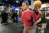Two beautiful, overweight women push their limits during a workout, supporting each other every step.
