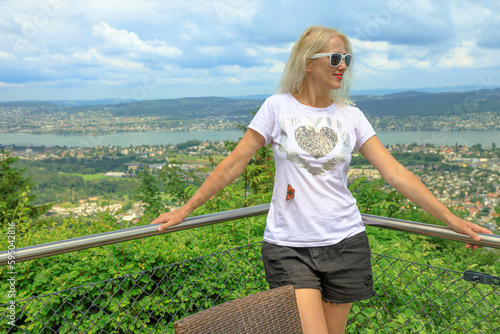 Girl with a butterfly on top of Zurich city and skyline from top of Felsenegg cable car. Blonde tourist woman by Zurich cityscape in Deutch Switzerland of Canton of Zurich. photo