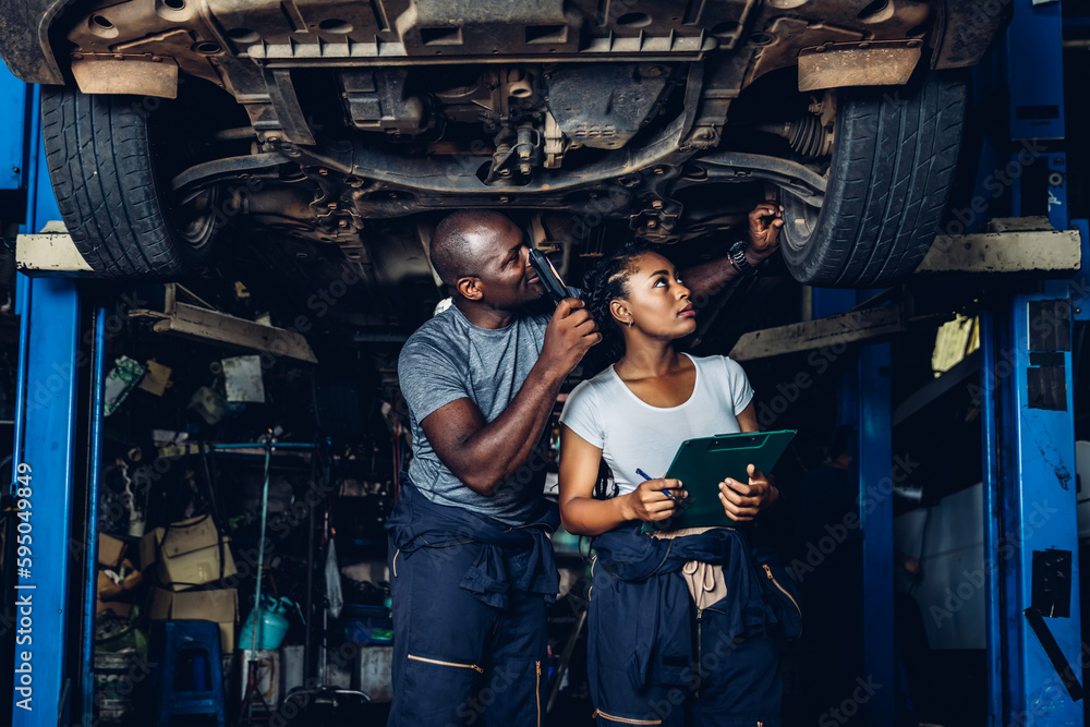 Professional Car Mechanic is Investigating Under a Vehicle on a Lift in Service. Auto Service Worker Checking Car Under Carriage Look For Issues. Car service technician check and repair customer car.