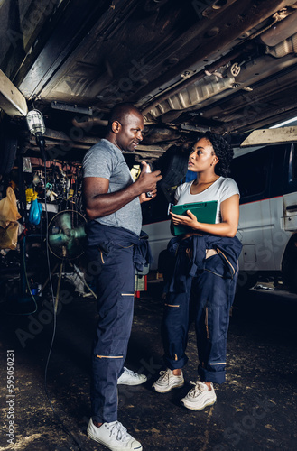 Professional Car Mechanic is Investigating Under a Vehicle on a Lift in Service. Auto Service Worker Checking Car Under Carriage Look For Issues. Car service technician check and repair customer car.