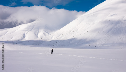 Winter landscape  man walking in snow valley surrounded by hills