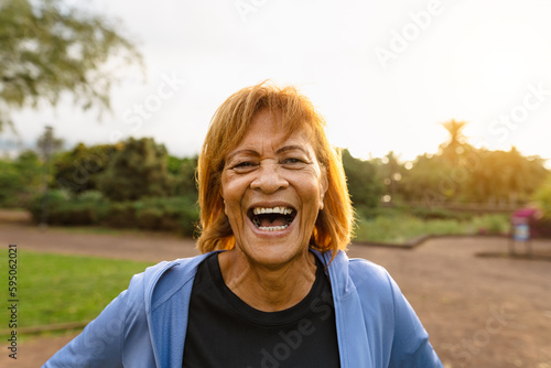 Happy senior Latin woman having fun smiling on camera after training activity in a public park