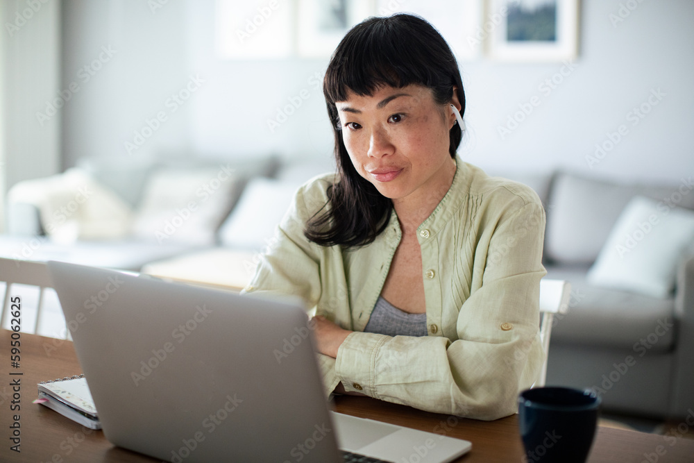 Young Japanese Woman working on a laptop in the kitchen Young Japanese Woman working on a laptop in the kitchen