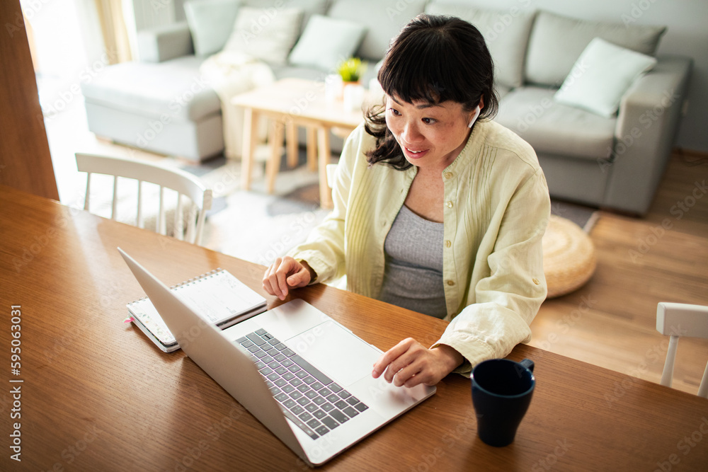 Young Japanese Woman working on a laptop in the kitchen