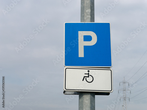 Close-up photo of a handicapped parking sign attached to a metal pole with the sky in the background