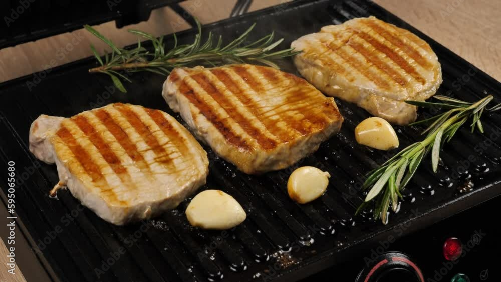 Delicious juicy meat steak cooked on the grill.Cooked juicy beef steak with rosemary and garlic on an electric grill Delicious juicy meat steak cooked on the grill.Cooked juicy beef steak with rosemary and garlic on an electric grill