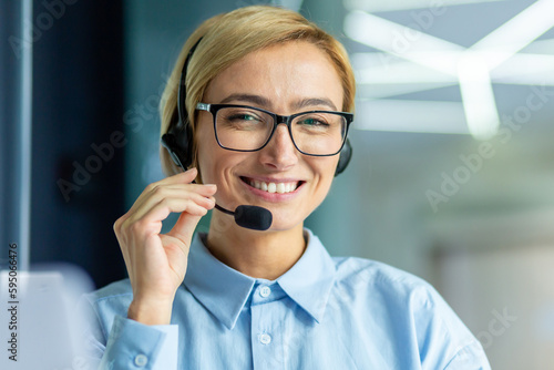 Portrait of successful female online customer support worker, close-up businesswoman smiling and looking at camera, helpline specialist using headset for video call and customer consultation.
