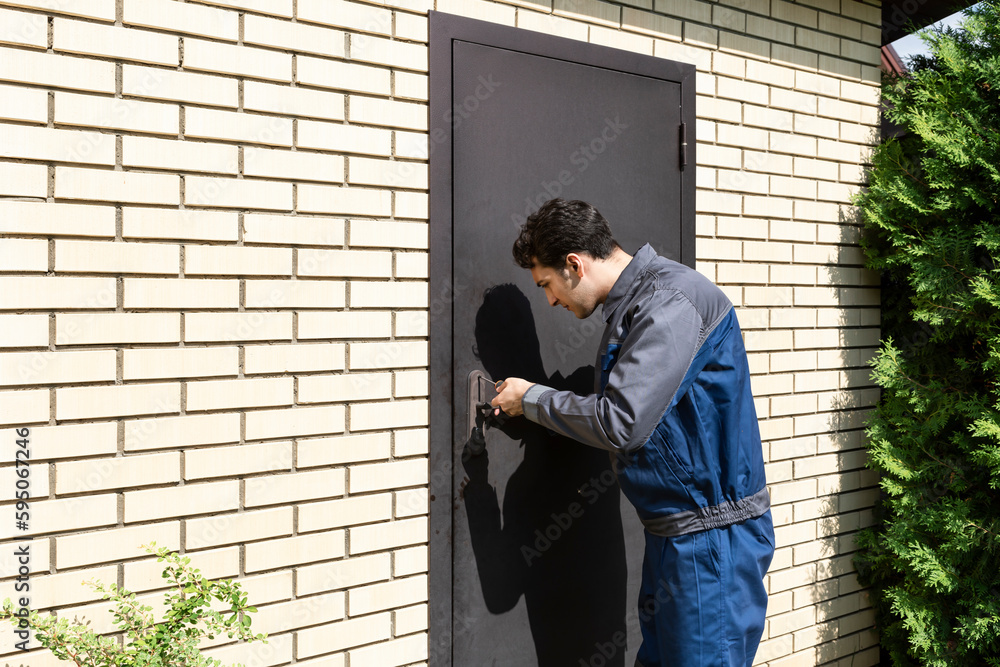Handsome repairman fixing the door on the backyard