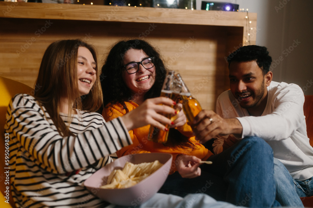 A group of friends watch a comedy movie sitting on soft bean bags with drinks and snacks. A group of friends watch a comedy movie sitting on soft bean bags with drinks and snacks.