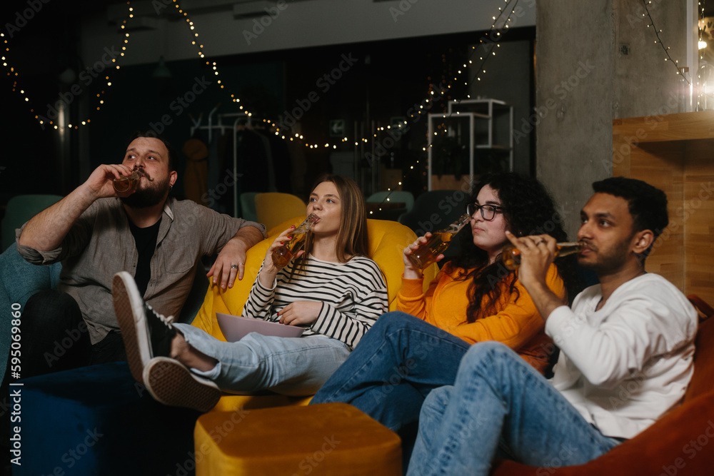 A company of friends in the evening in a cafe spend time together watching their favorite TV series.