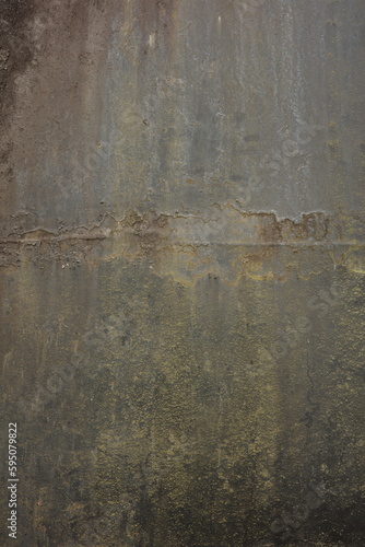 An old metal surface tarnished over time, with signs of weathering that have deteriorated the metal material. A dirty, dull gray color.