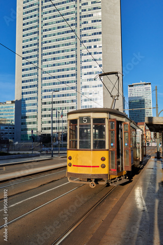 vintage tram in the city at early morning with glass skyscrapers in background in business district of milan