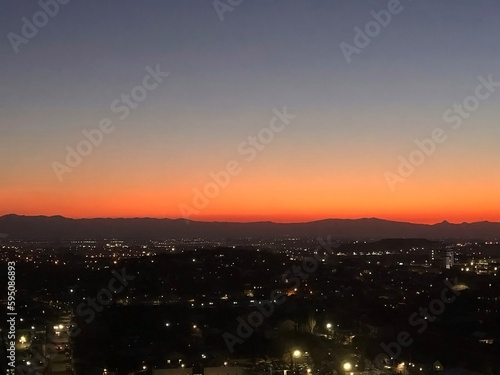 Aerial view of city center in the night lights at sunset and mountain on the horizon