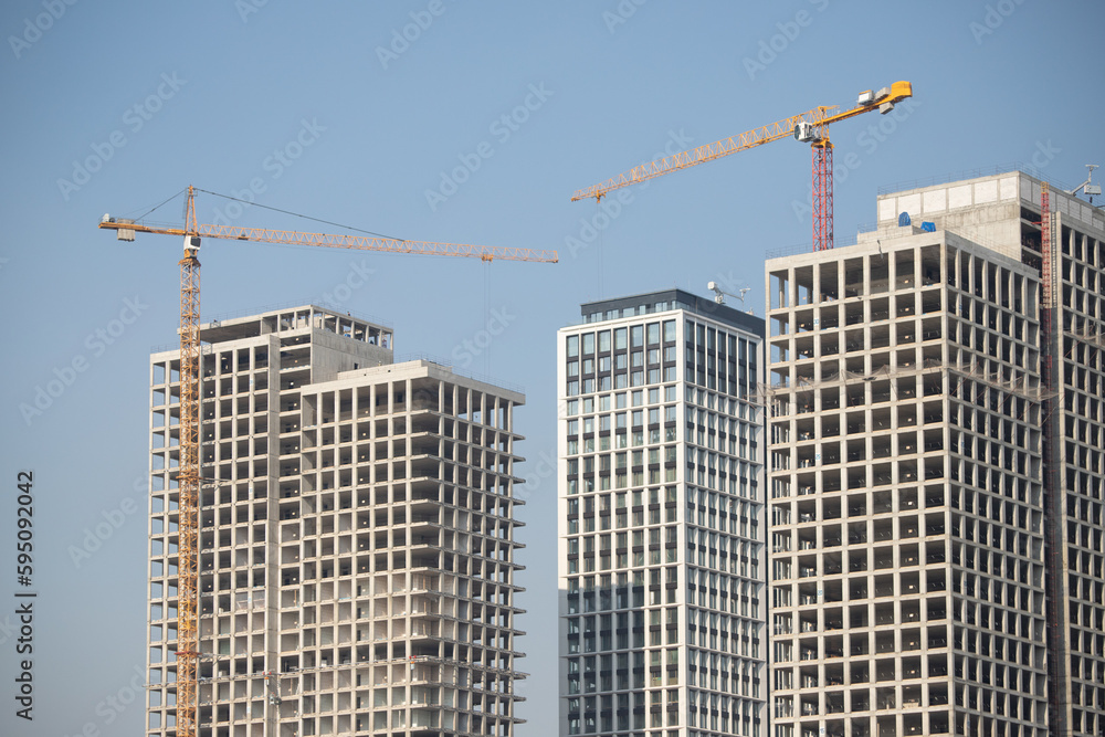 The structure of multi-storey buildings, tower cranes against the blue sky.