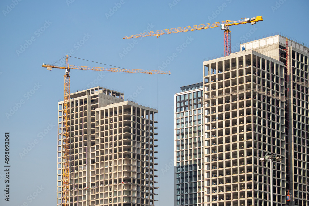 The structure of multi-storey buildings, tower cranes against the blue sky.