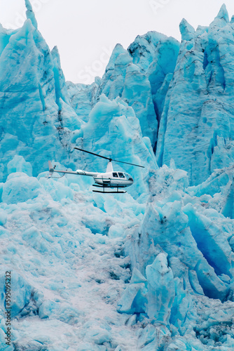 Alaska, Kenai Peninsula. Helicopter flying in front of the Aialik Glacier. photo