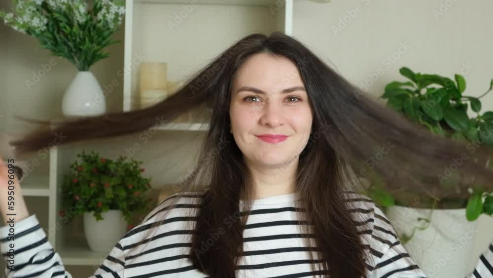 30-year-old brunette woman touching her hair with her hands and smiling while looking at the camera 30-year-old brunette woman touching her hair with her hands and smiling while looking at the camera