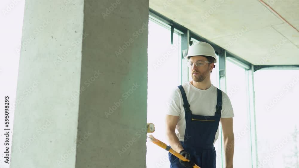 Construction worker moving paint roller on wall in new office or apartment Construction worker moving paint roller on wall in new office or apartment