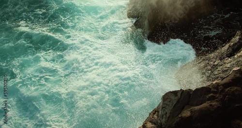 Ocean waves foaming splshing on rocky shore. Raging severe sea turquoise water close-up cinematic view. photo