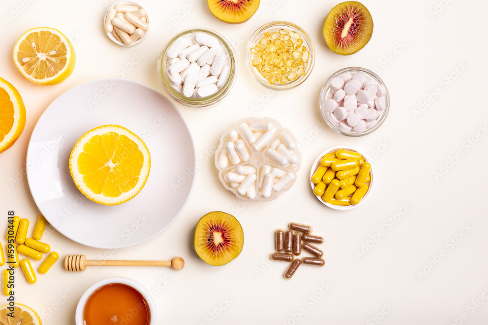Many jars filled with dietary supplements, vitamins and minerals in form of pills, capsules and tablets. Orange on white round plate, honey and kiwi from above on light background. Healthy lifestyle. Many jars filled with dietary supplements, vitamins and minerals in form of pills, capsules and tablets. Orange on white round plate, honey and kiwi from above on light background. Healthy lifestyle.