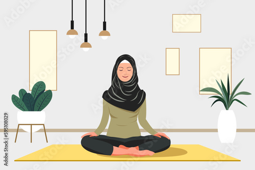 Yoga studio at home. Muslim women  sits in a meditation pose on a mat. Yoga classes at home. Interior of a modern apartment. Yoga concept.