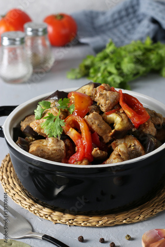 Braised pork with eggplant and tomatoes in a ceramic dish on gray background, Closeup