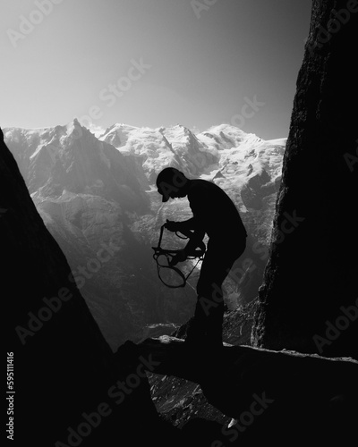 man climber prepares to put on the harness to climb the rock needles near chamonix, in the background the mont blanc peak massif, in the french alps photo
