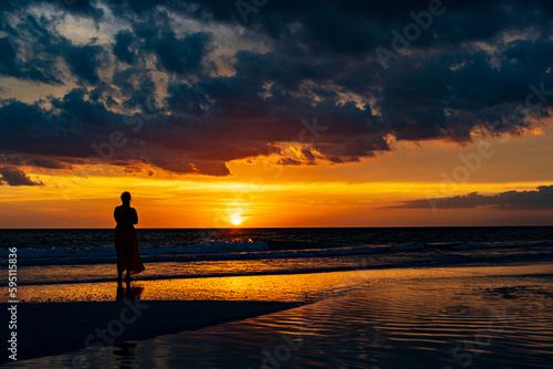 a woman watches sunset in a tropical paradise