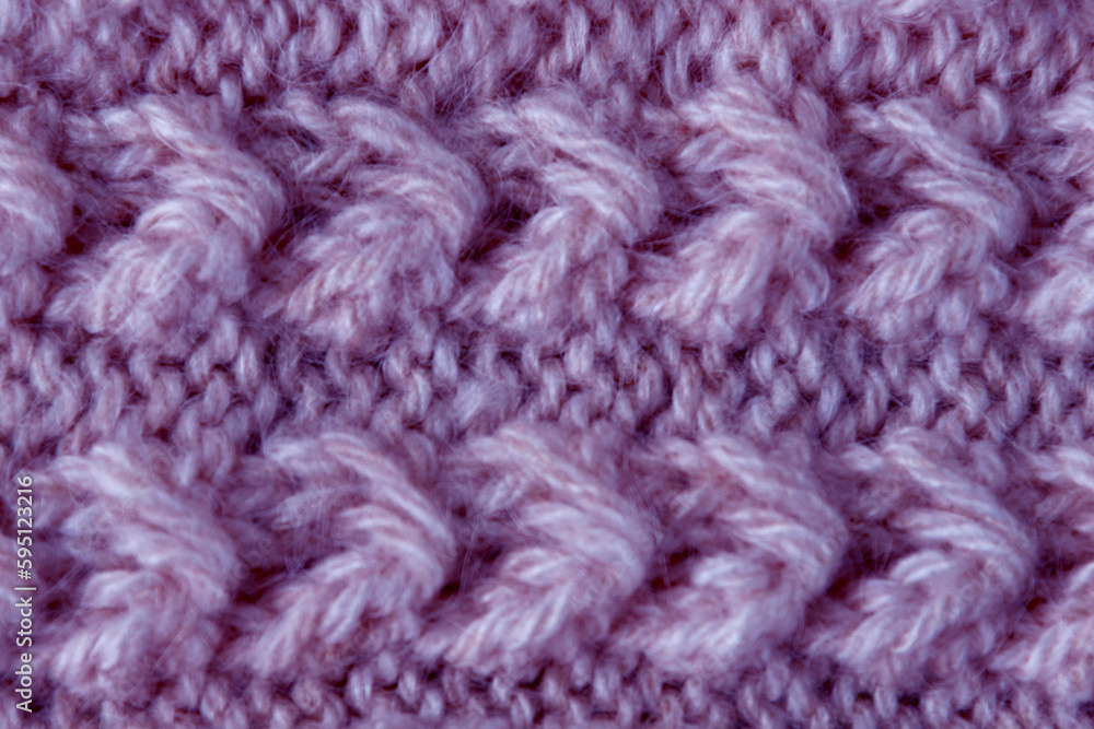 The texture of the fabric of a lilac woolen sweater with a pattern. Handmade