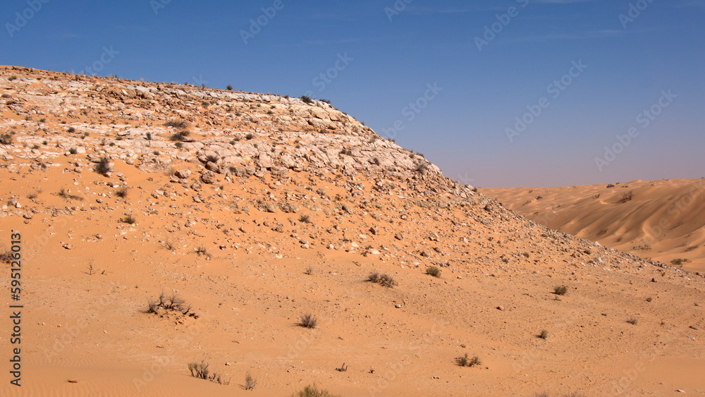 Rock topped hill in a valley surrounded by sand dunes in the Sahara Desert, outside of Douz, Tunisia