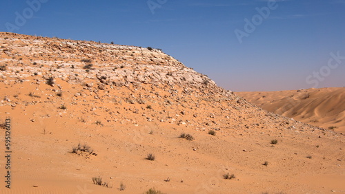 Rock topped hill in a valley surrounded by sand dunes in the Sahara Desert  outside of Douz  Tunisia